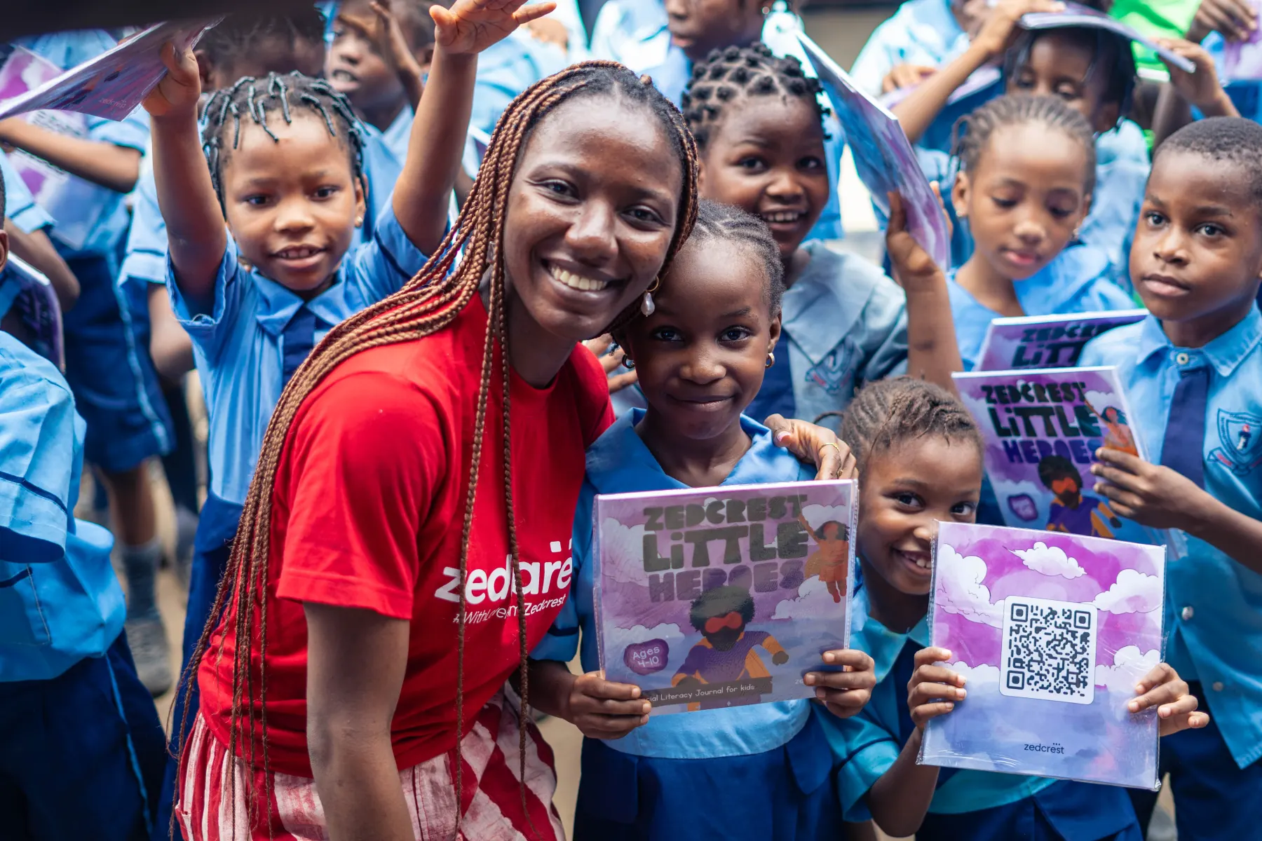 A Zedcrest team member with pupils holding their Little Heroes books